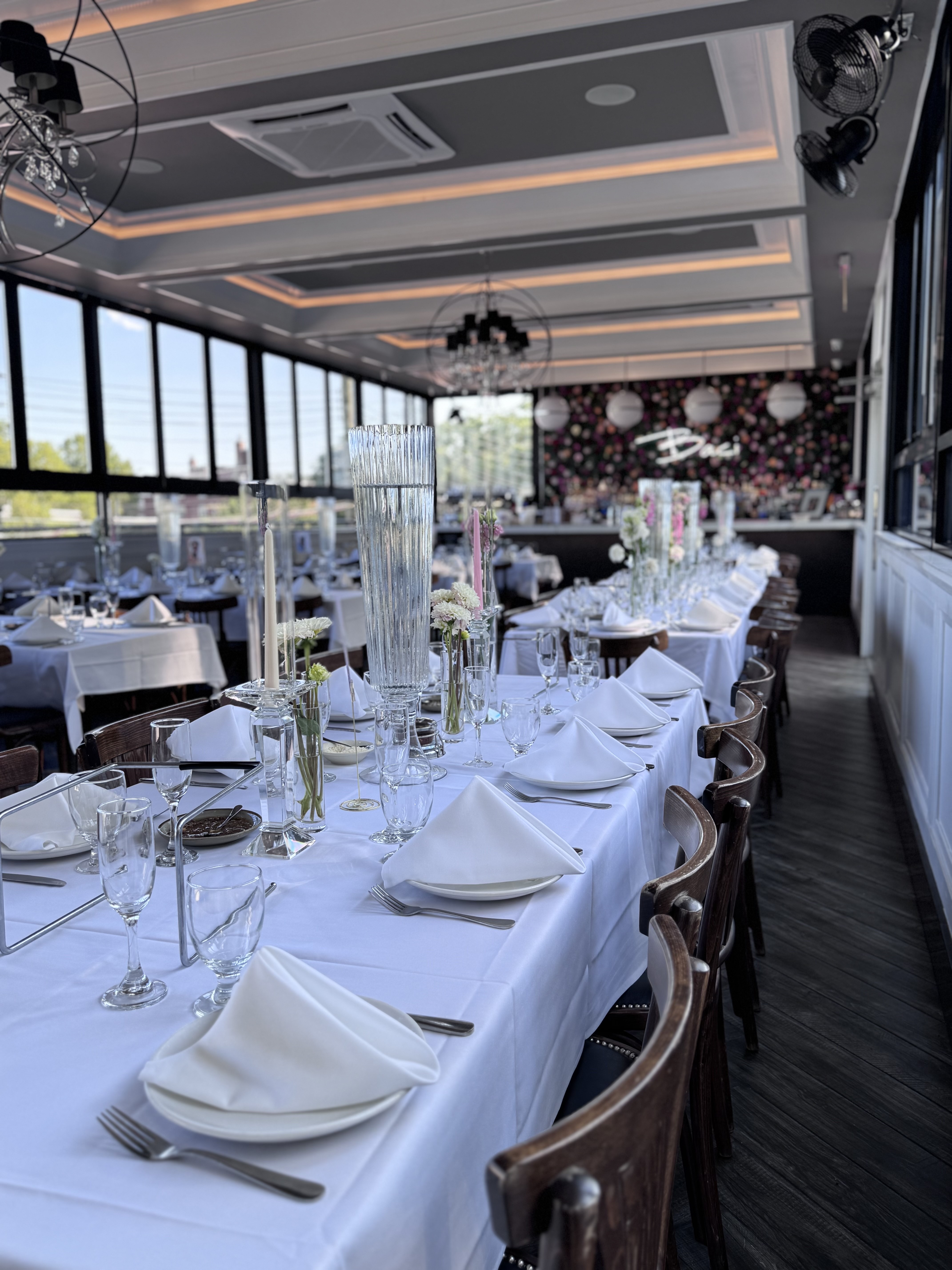 The Rooftop set for a wedding with long tables, pink florals and orb chandeliers